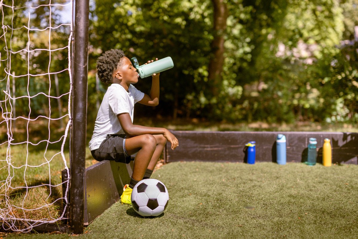 Young boy drinking a water bottle on soccer field